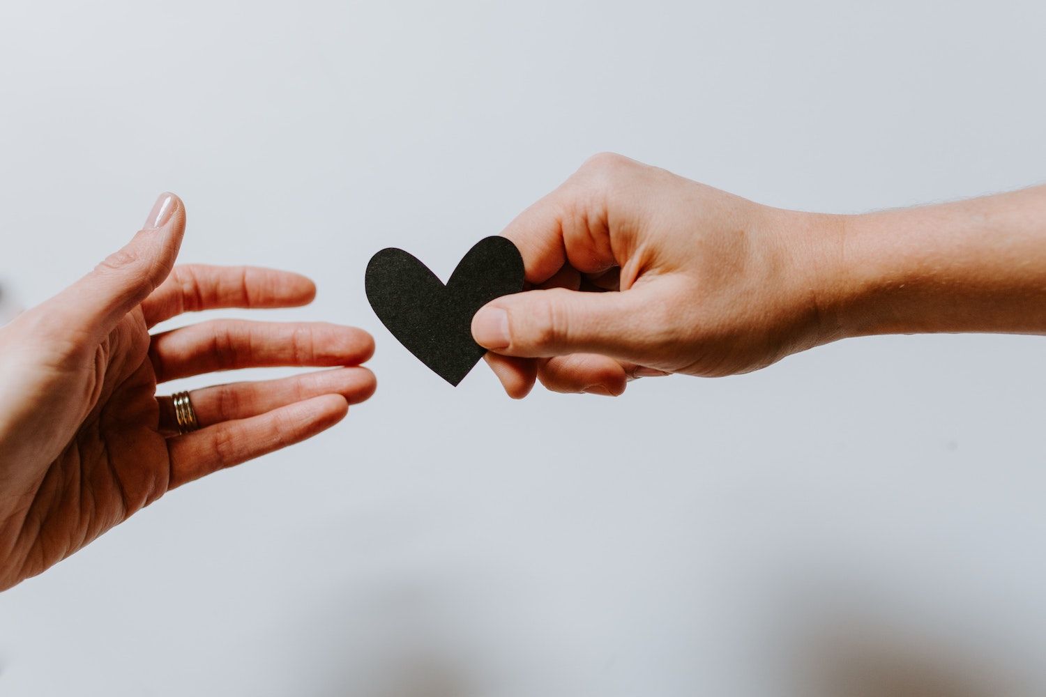 A hand passing a paper heart to another hand  